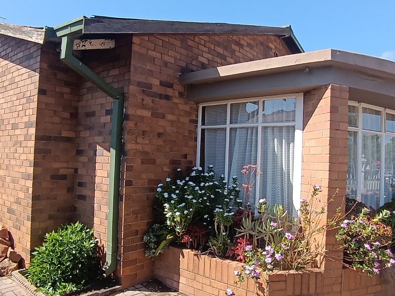 A view of the front facade featuring face brick construction, a curved brick planter box, and paved driveway access.