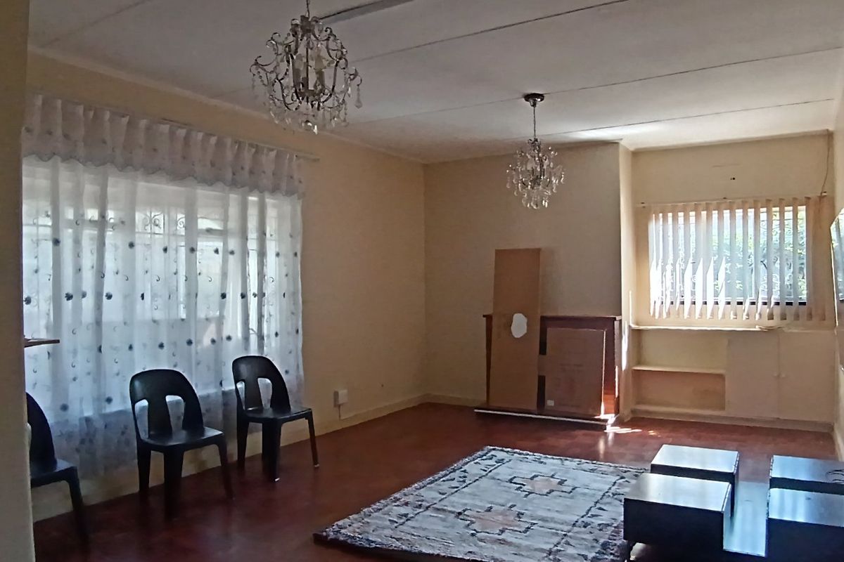 Spacious living room featuring laminate flooring, built-in shelving, and dual crystal chandeliers, offering a versatile layout for comfortable family living.