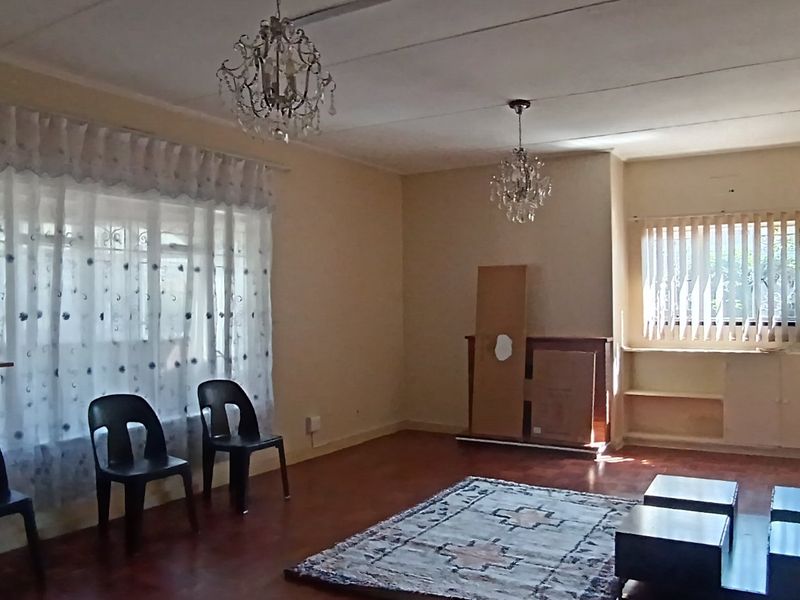 Spacious living room featuring laminate flooring, built-in shelving, and dual crystal chandeliers, offering a versatile layout for comfortable family living.