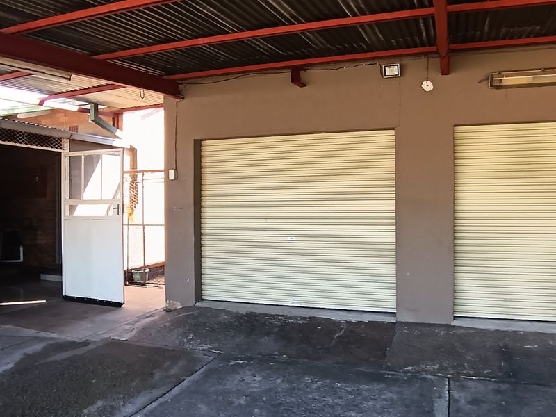 A functional double garage featuring dual roller doors, a covered entrance area, and a durable concrete driveway.