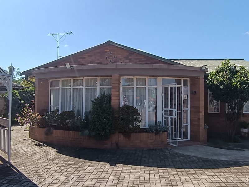 Rear view of a brick house featuring a paved courtyard area and a decorative metal gazebo structure.