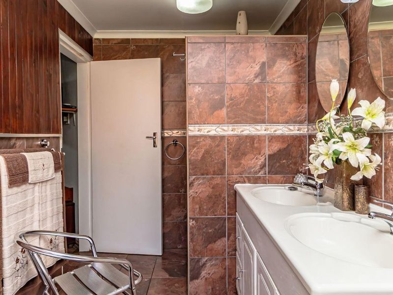 A bathroom featuring a double vanity with integrated sinks, tiled walls and flooring, and a separate shower enclosure.