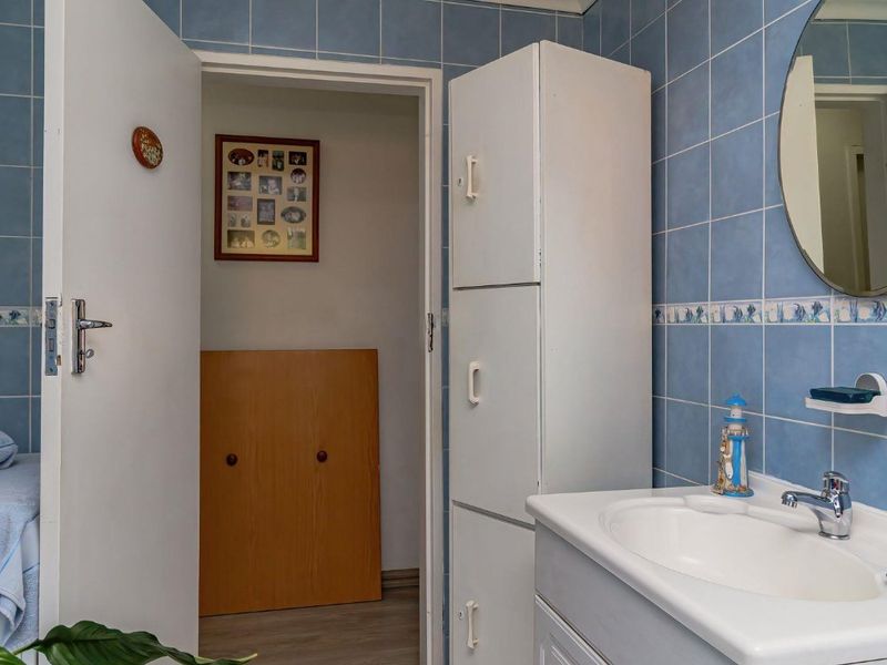 A functional bathroom featuring blue wall tiles, a built-in vanity with basin, and additional built-in storage cabinetry.