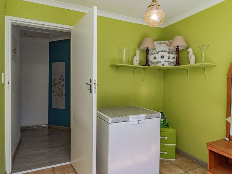 A bedroom featuring lime green walls, tiled flooring, and built-in shelving, with an open doorway leading to an adjacent hallway.