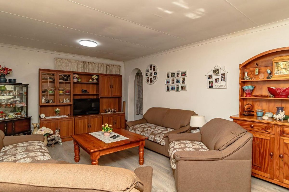 A comfortable living room featuring laminate flooring, an archway entrance, and a wall-mounted air conditioning unit.