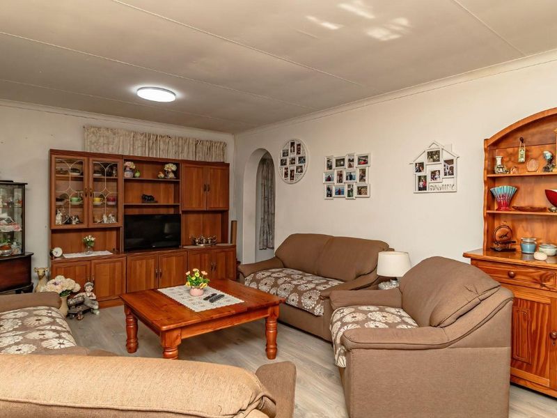 A comfortable living room featuring laminate flooring, an archway entrance, and a wall-mounted air conditioning unit.