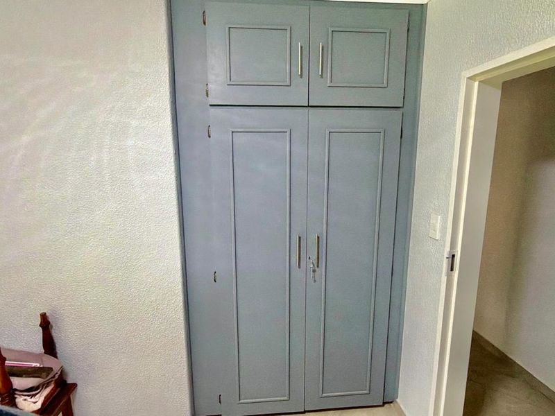 A bedroom featuring a built-in cupboard with blue painted doors and modern silver handles.