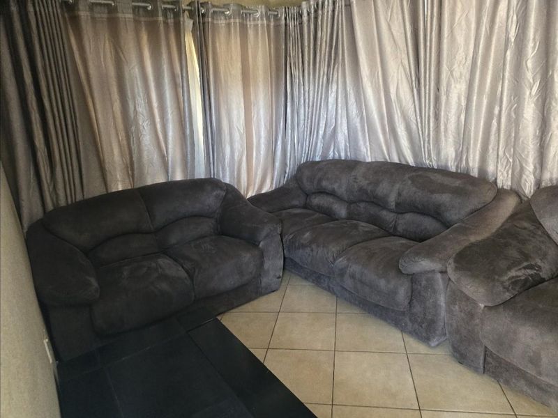A living room area featuring tiled flooring and full-length curtain treatments.