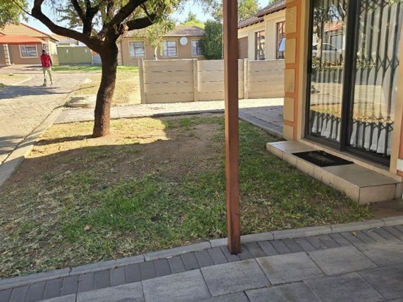 A covered paved patio area overlooking a small garden with a precast concrete boundary wall and sliding door access to the home.