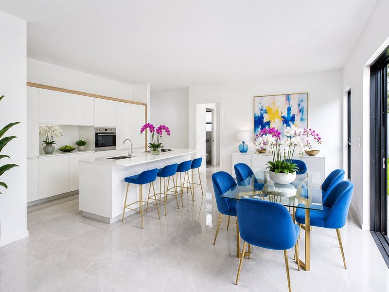 Modern open-plan kitchen and dining area featuring sleek white cabinetry, a central island, and large sliding doors opening to the garden.