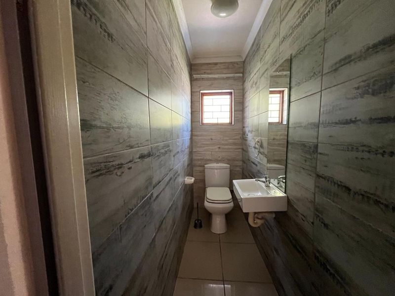 A compact, modern bathroom featuring full-height wood-look wall tiles, a wall-mounted basin, and a standard toilet.
