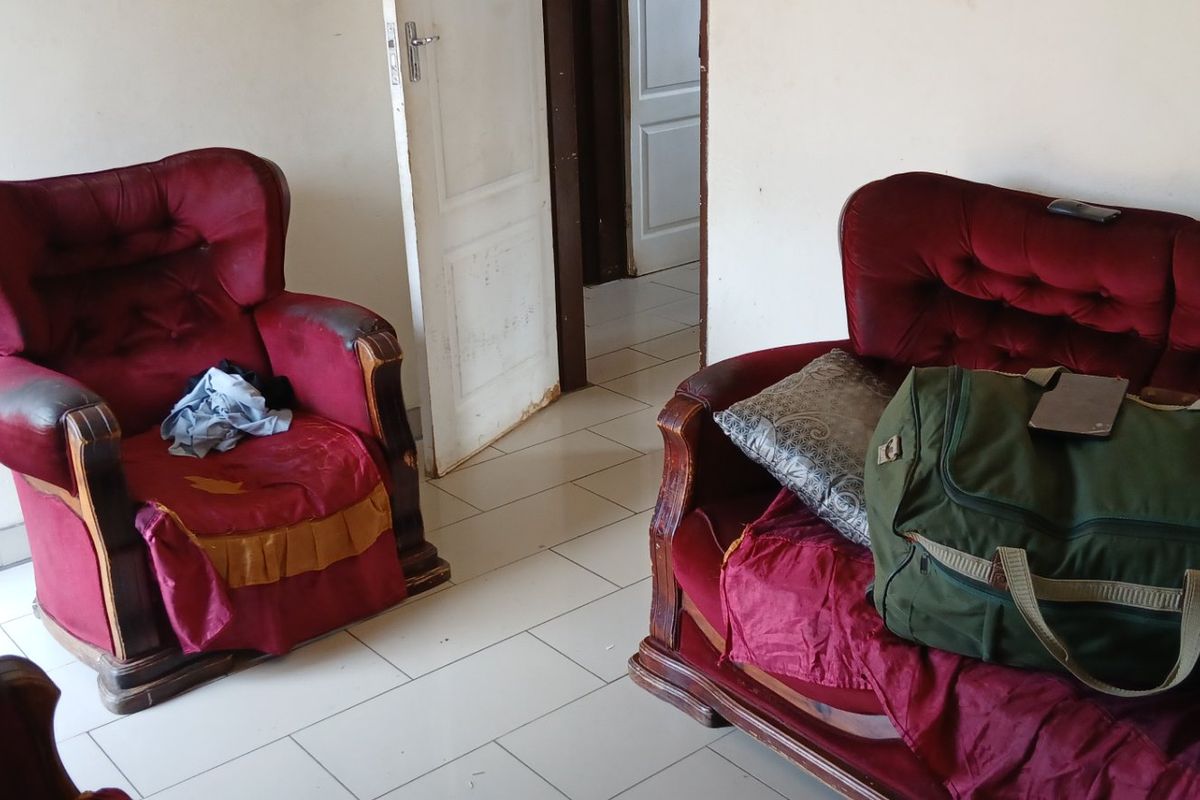 A living room area featuring tiled flooring and a standard internal door with visible wear on the door frame.