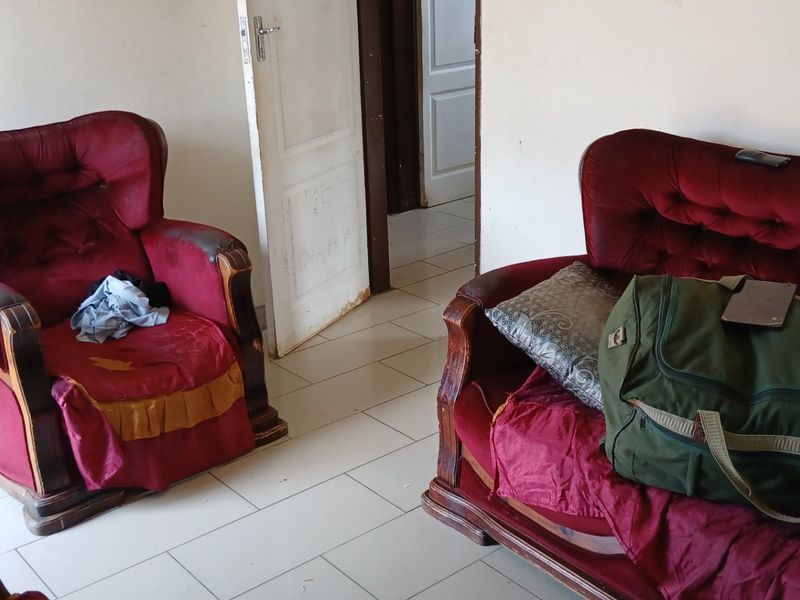 A living room area featuring tiled flooring and a standard internal door with visible wear on the door frame.