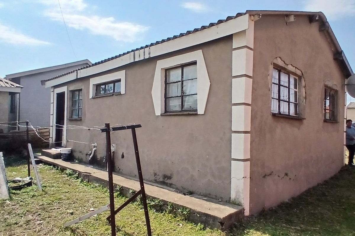 Rear view of a detached house showing exterior plaster walls, steel-framed windows, and a tiled roof structure.
