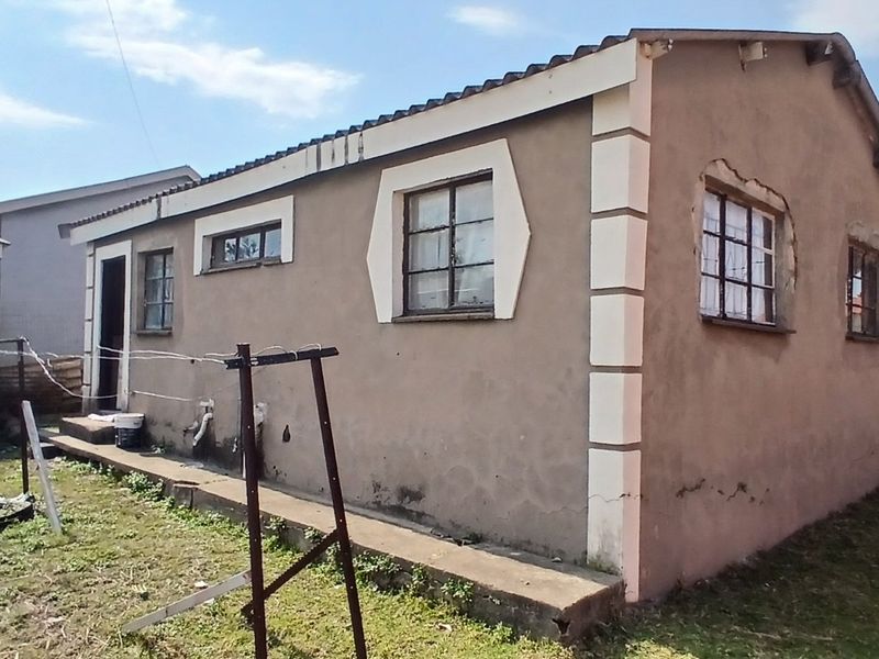 Rear view of a detached house showing exterior plaster walls, steel-framed windows, and a tiled roof structure.