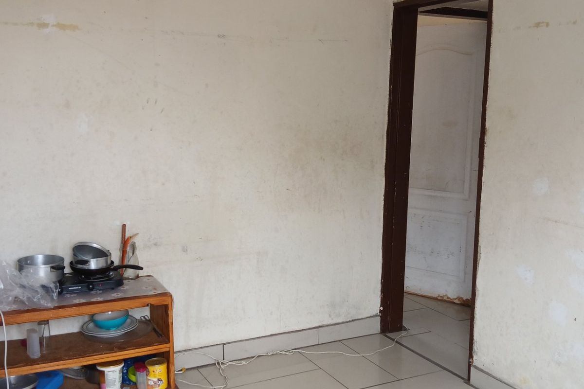 A basic kitchen area featuring tiled flooring and plain walls, currently requiring cosmetic updates and maintenance to improve the overall finish.
