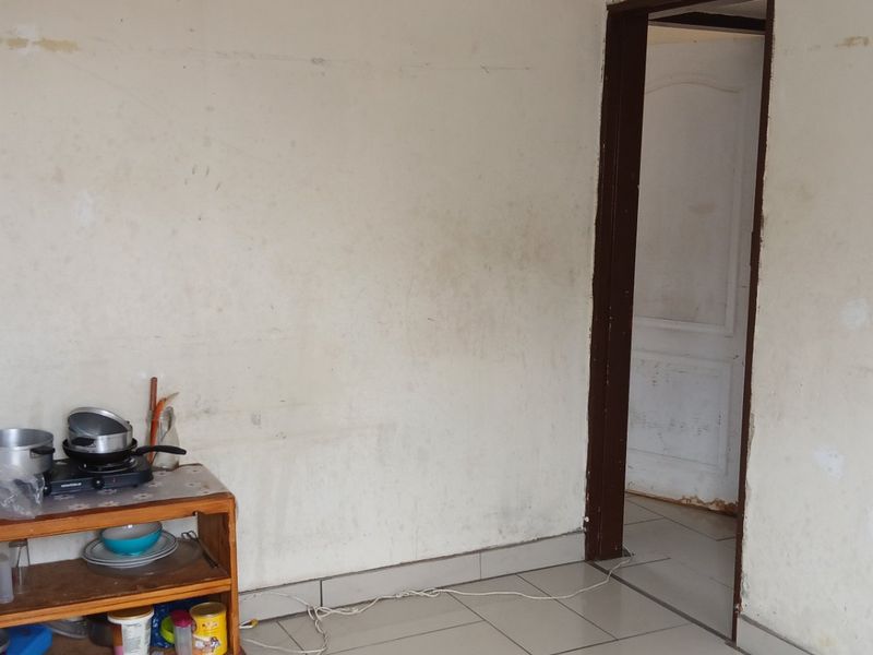 A basic kitchen area featuring tiled flooring and plain walls, currently requiring cosmetic updates and maintenance to improve the overall finish.