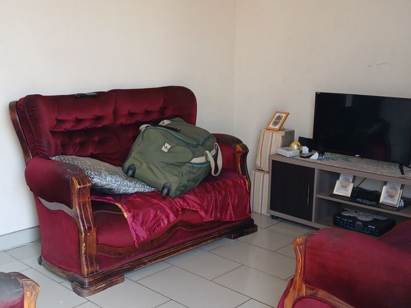 A compact living room area featuring tiled flooring and neutral wall finishes, providing a functional space for relaxation.