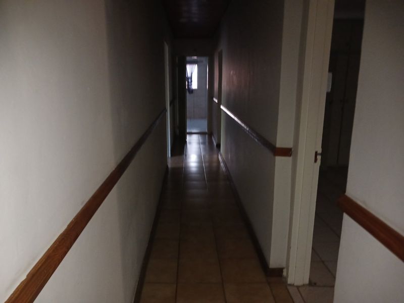 A narrow interior hallway featuring tiled flooring and wooden dado rails, providing access to adjacent rooms.