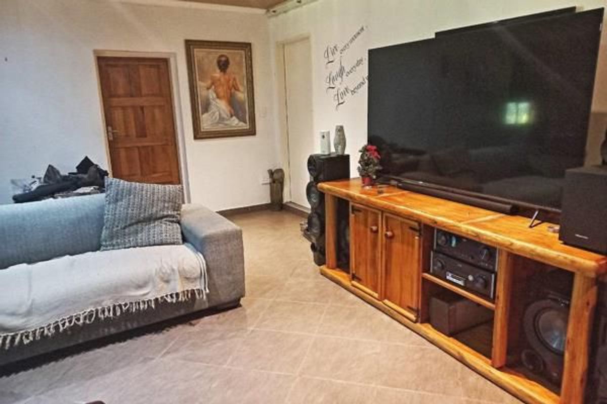 A living room area featuring tiled flooring and a wooden door, providing a functional space for relaxation.