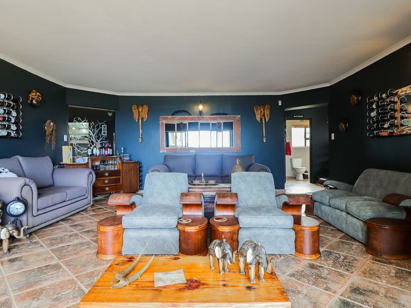 Spacious living room featuring dark-painted walls, tiled flooring, and wall-mounted lighting, providing a cozy and distinct atmosphere.