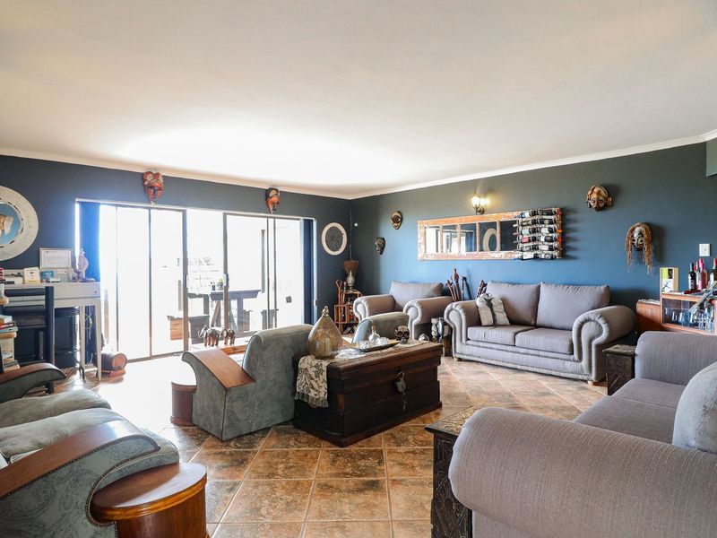 Spacious living room featuring tiled flooring, dark accent walls, and large sliding glass doors providing access to the outdoor area.