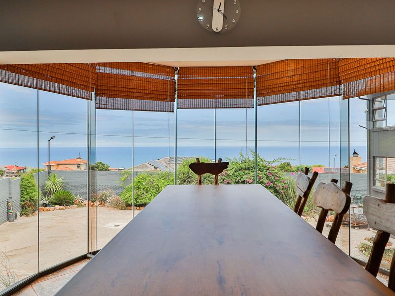 Dining area featuring expansive frameless glass stacking doors that provide panoramic ocean views and seamless access to the outdoor space.