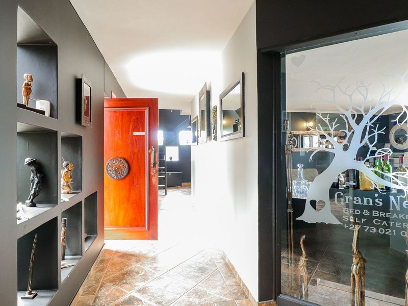 An inviting entrance hall featuring tiled flooring, built-in wall display niches, and a solid wood front door leading into the property.