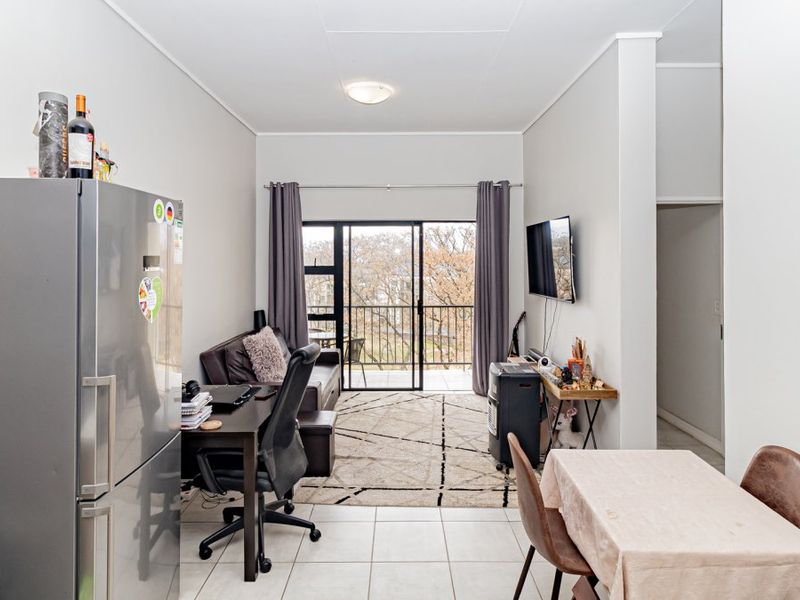 Open-plan living area featuring tiled flooring and a sliding glass door leading to a balcony, providing natural light and outdoor access.