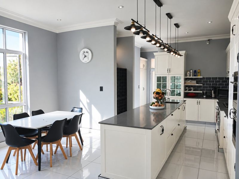 Modern open-plan kitchen featuring a large central island with stone countertops, sleek cabinetry, subway tile backsplash, and contemporary pendant lighting.