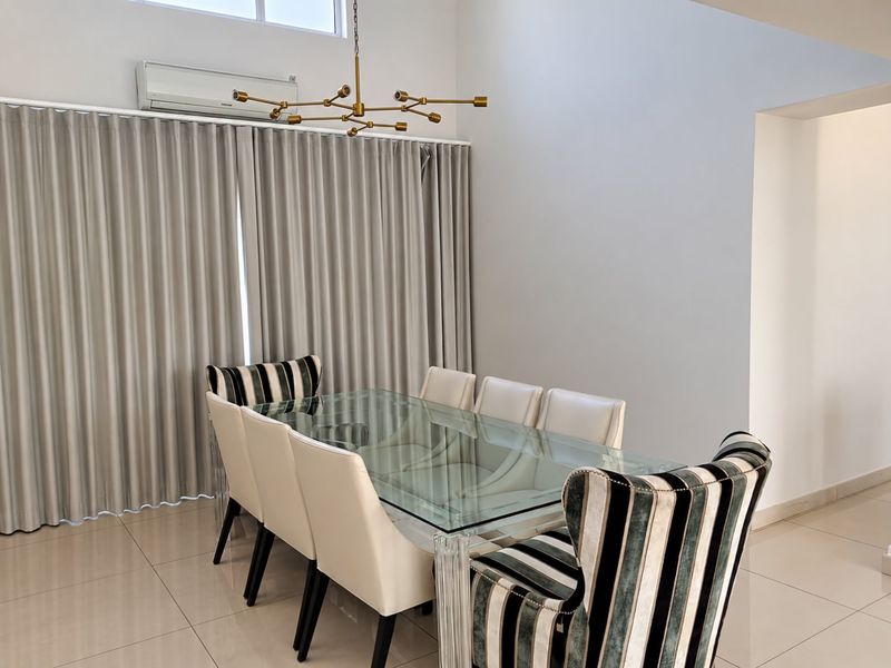 A bright dining room featuring high ceilings, tiled flooring, a split-system air conditioner, and a large window allowing for natural light.