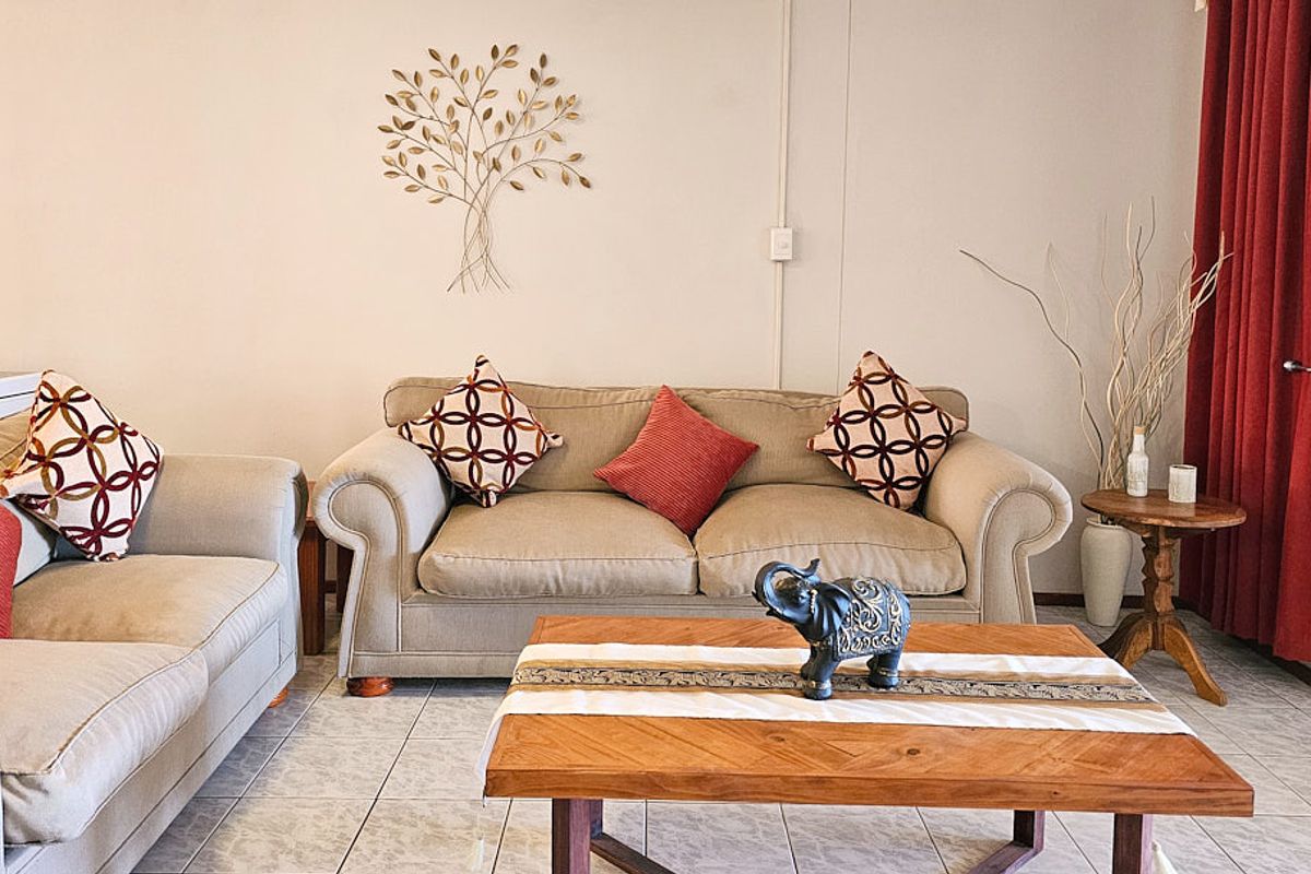 A comfortable living room area featuring neutral ceramic floor tiles and access to an outdoor space through a sliding glass door.