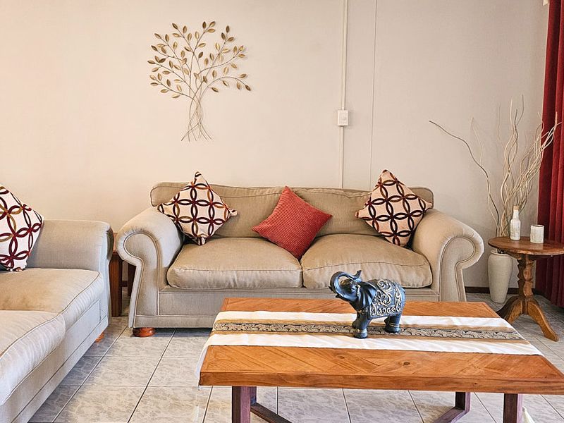 A comfortable living room area featuring neutral ceramic floor tiles and access to an outdoor space through a sliding glass door.