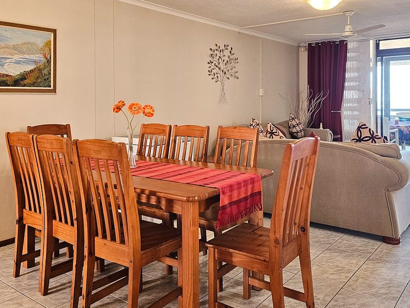 Open plan living and dining area featuring tiled flooring, a ceiling fan, and large sliding glass doors leading to an outdoor balcony.