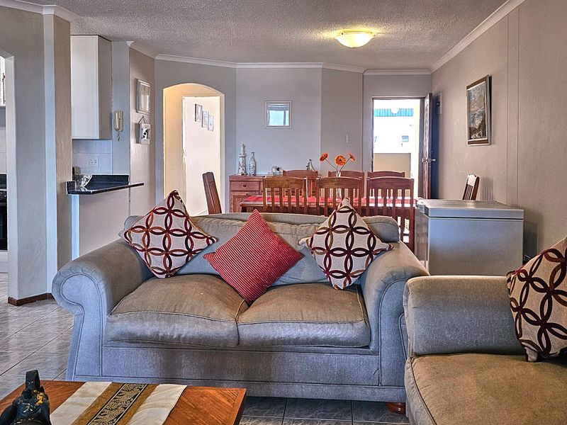 Open-plan living and dining area featuring tiled floors, an adjoining kitchen with built-in cabinetry, and a functional layout connecting to the rest of the apartment.