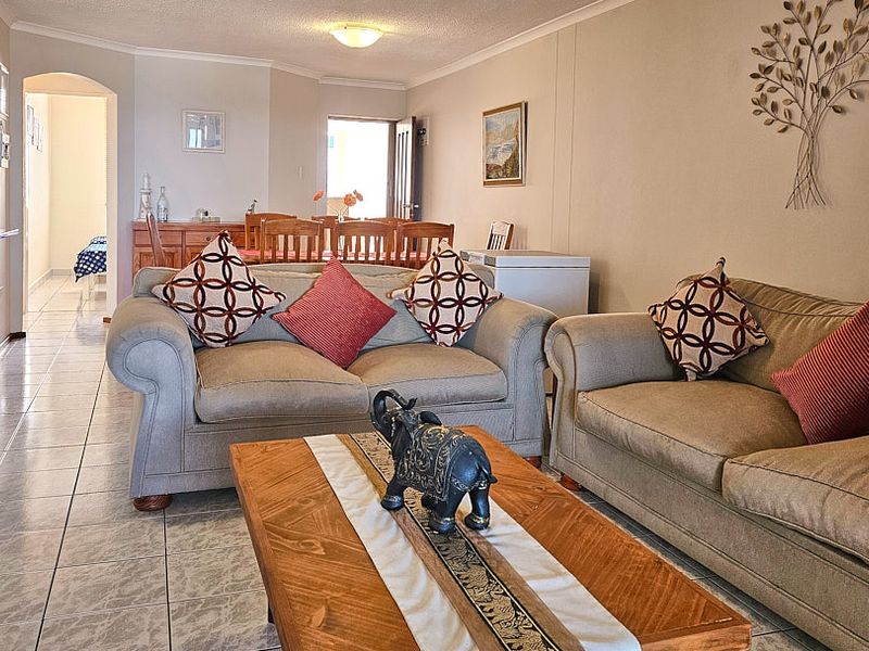 An open-plan living and dining area featuring neutral wall tones, tiled flooring, and an archway leading to the hallway.