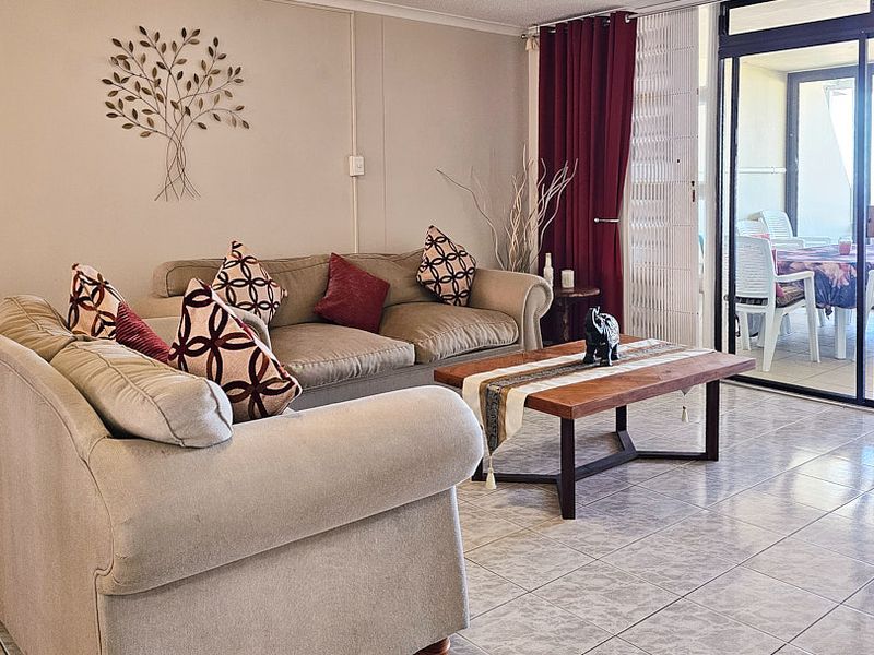 A comfortable living room featuring tiled flooring and a large sliding glass door that provides access to an outdoor patio area.