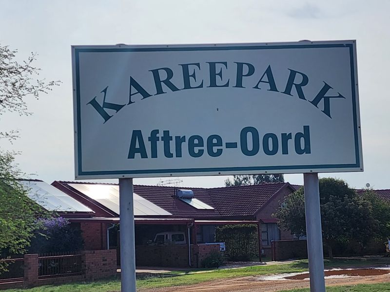 Street view of the Kareepark Aftree-Oord residential complex entrance, featuring brick townhouse facades and installed solar panels.