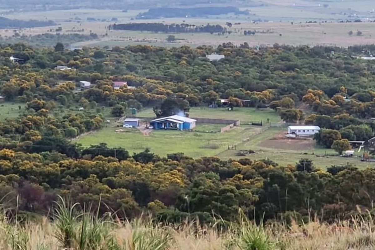 An elevated aerial view of a rural property setting featuring scattered residential buildings surrounded by natural vegetation and open landscape.