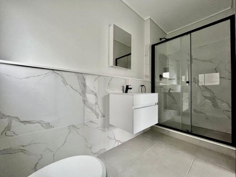 Modern bathroom featuring a floating vanity, walk-in shower with glass enclosure, and elegant marble-look wall tiling with contemporary black fixtures.