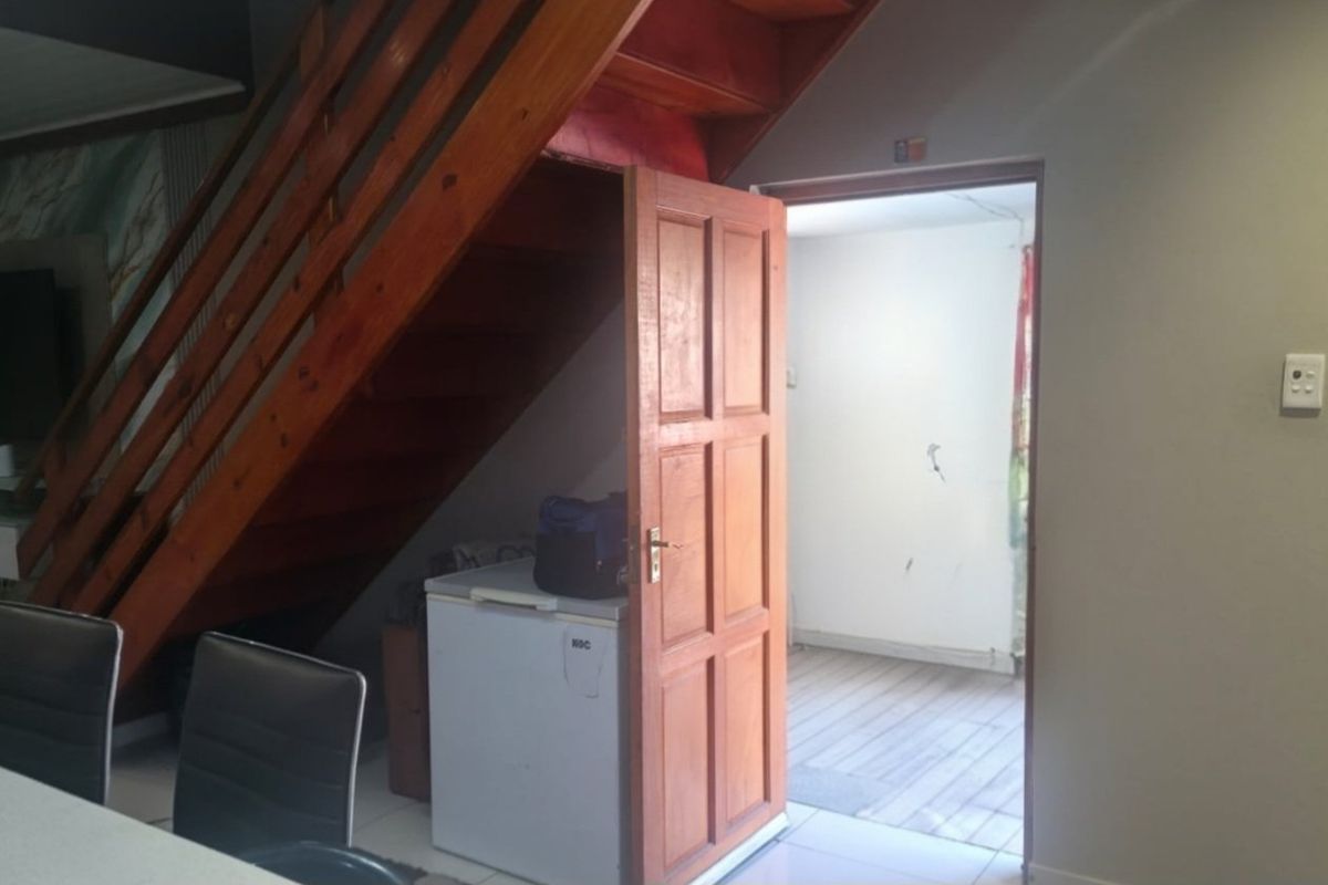 Living area featuring a wooden staircase and tiled flooring, providing access to an adjacent room.