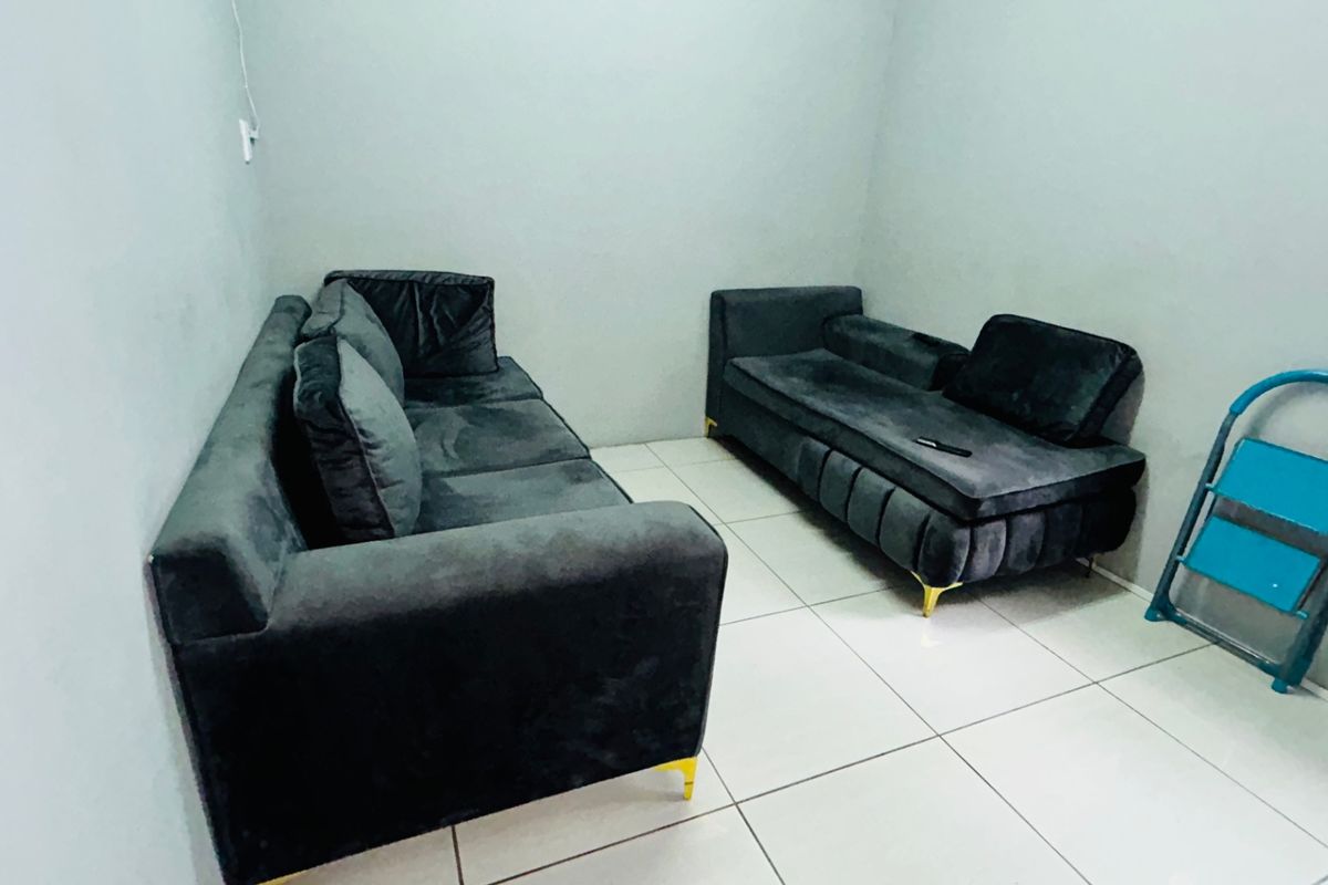 A simple living area featuring neutral wall finishes and tiled flooring, providing a functional space for commercial or office use.