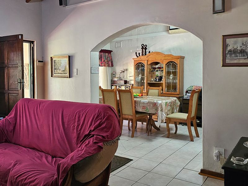 Open plan living and dining area featuring an arched transition, tiled flooring, and traditional architectural details.