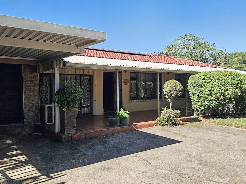 Front elevation of a single-story house featuring a covered patio, attached carport, and a concrete driveway.
