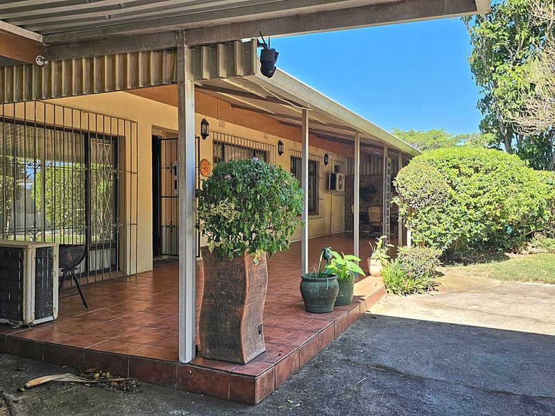 A covered outdoor patio area featuring tiled flooring, stone cladding accents, and security fixtures, providing a functional space for outdoor living.