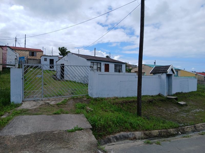 Front exterior view of a detached house featuring a perimeter wall, metal security gate, and tiled roof structure.