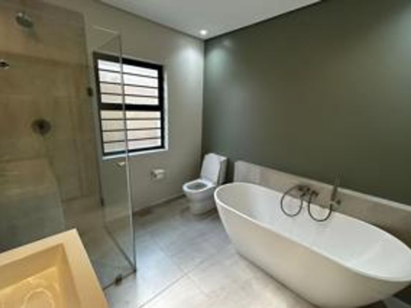 Modern bathroom featuring a sleek freestanding bathtub, a spacious glass-enclosed shower, and contemporary fixtures with neutral wall tones.