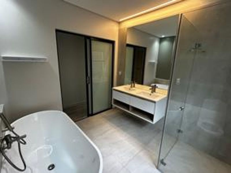 Modern, spacious bathroom featuring a sleek freestanding bathtub, a contemporary double vanity, and a large walk-in shower with glass enclosure.