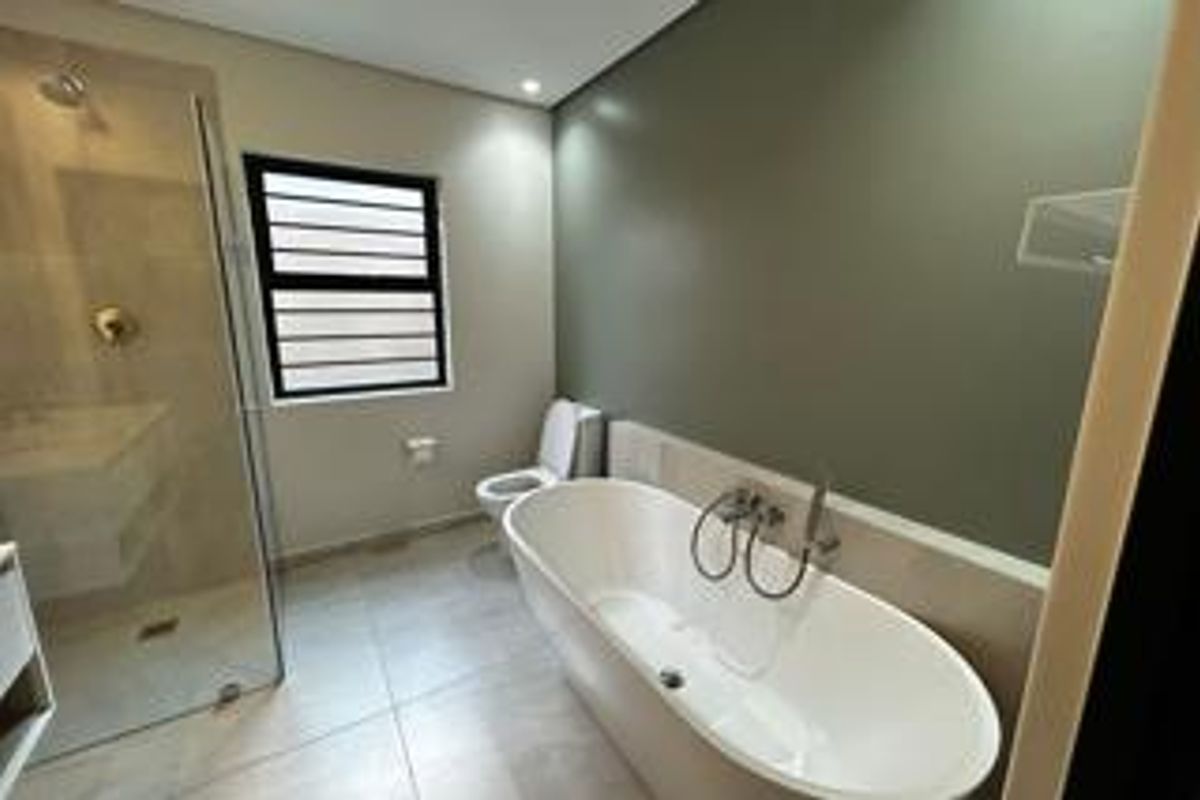 Modern bathroom featuring a sleek freestanding bathtub, a spacious glass-enclosed shower, and contemporary tiled finishes.