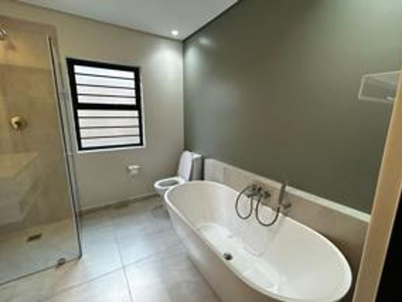 Modern bathroom featuring a sleek freestanding bathtub, a spacious glass-enclosed shower, and contemporary tiled finishes.